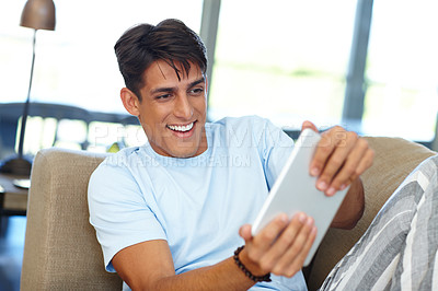 Buy stock photo Cropped shot of a young man using his digital tablet at home