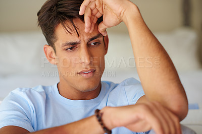 Buy stock photo Cropped shot of a handsome young looking contemplative while sitting at home