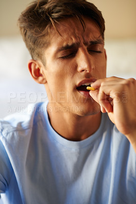 Buy stock photo Shot of a young man taking medication