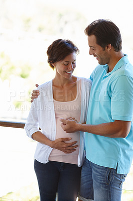 Buy stock photo Shot of a man standing beside his pregnant wife