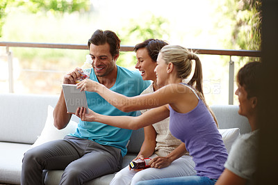 Buy stock photo Shot of a group of friends looking at something on a tablet while relaxing on the sofa