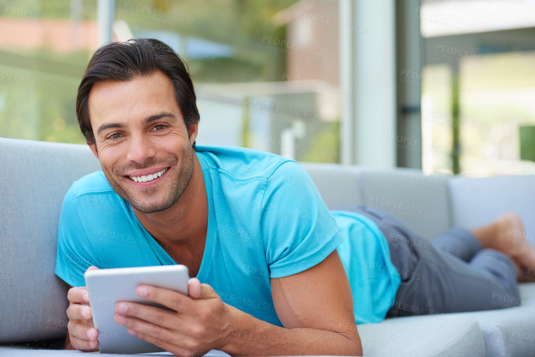 Buy stock photo Portrait of a handsome man lying on the sofa with his digital tablet