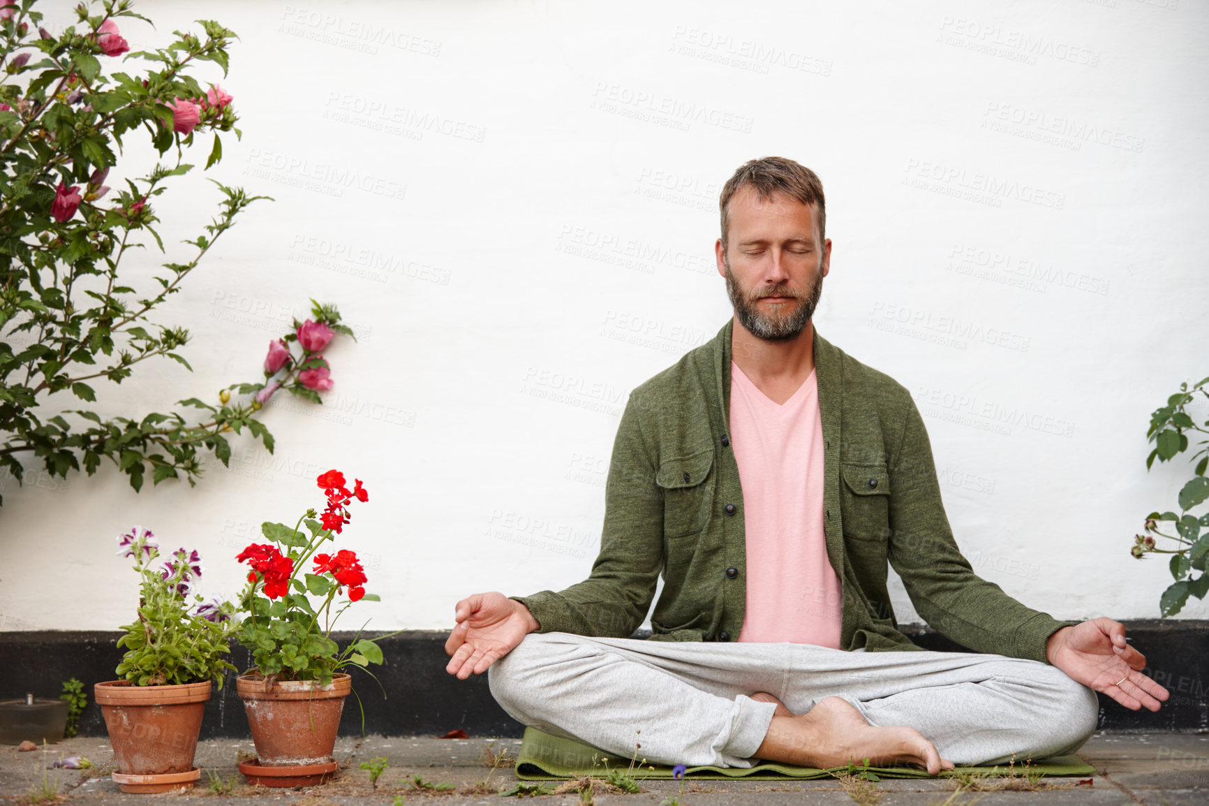 Buy stock photo Shot of a handsome mature man meditating in the lotus position in a courtyard