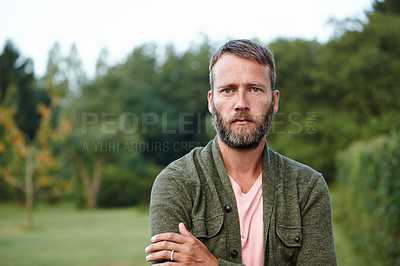 Buy stock photo Portrait of a serious man standing with his arms crossed at the park. Closeup of a mature male farmer alone in the countryside. Stressed out guy getting away from it all and spending time in nature 