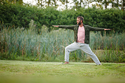 Buy stock photo Shot of a handsome mature man doing yoga at a park