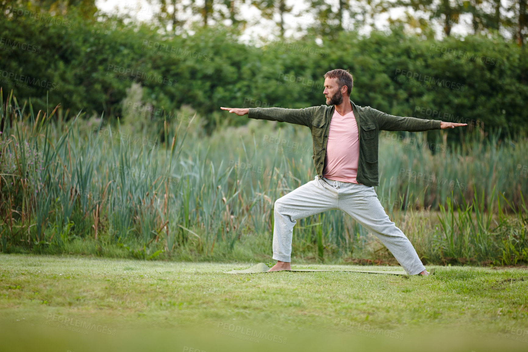 Buy stock photo Shot of a handsome mature man doing yoga at a park