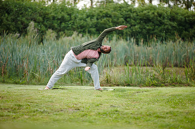 Buy stock photo Shot of a handsome mature man doing yoga at a park