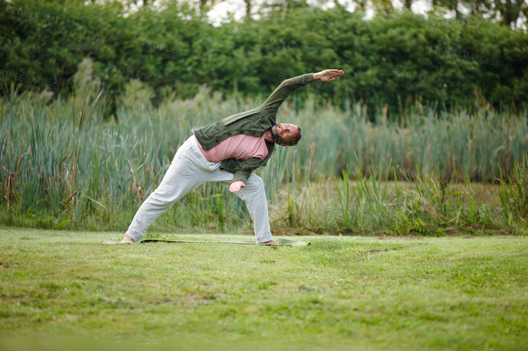 Buy stock photo Shot of a handsome mature man doing yoga at a park