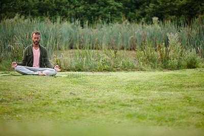 Buy stock photo Shot of a handsome mature man meditating in the lotus position in nature