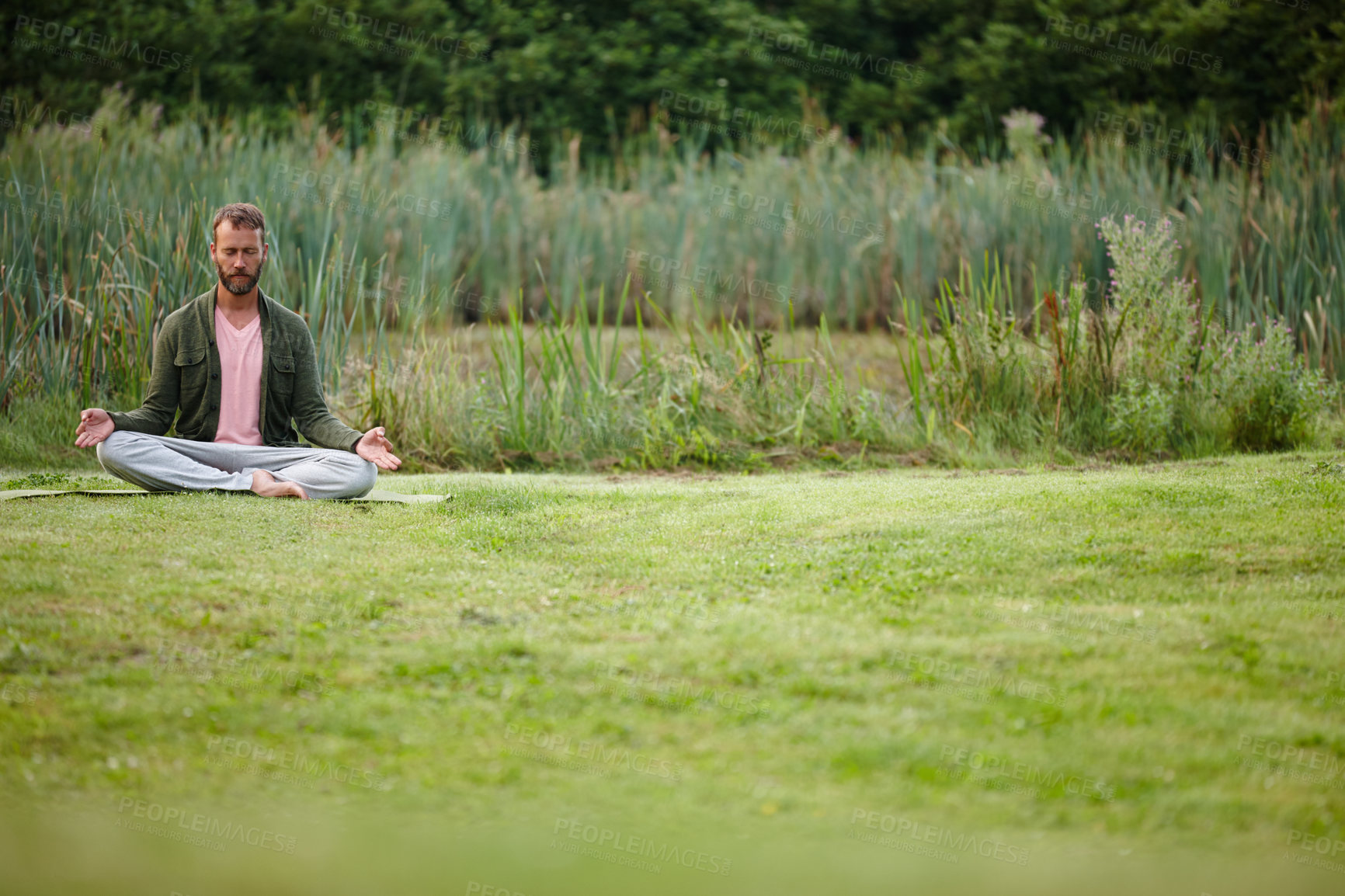 Buy stock photo Shot of a handsome mature man meditating in the lotus position in nature