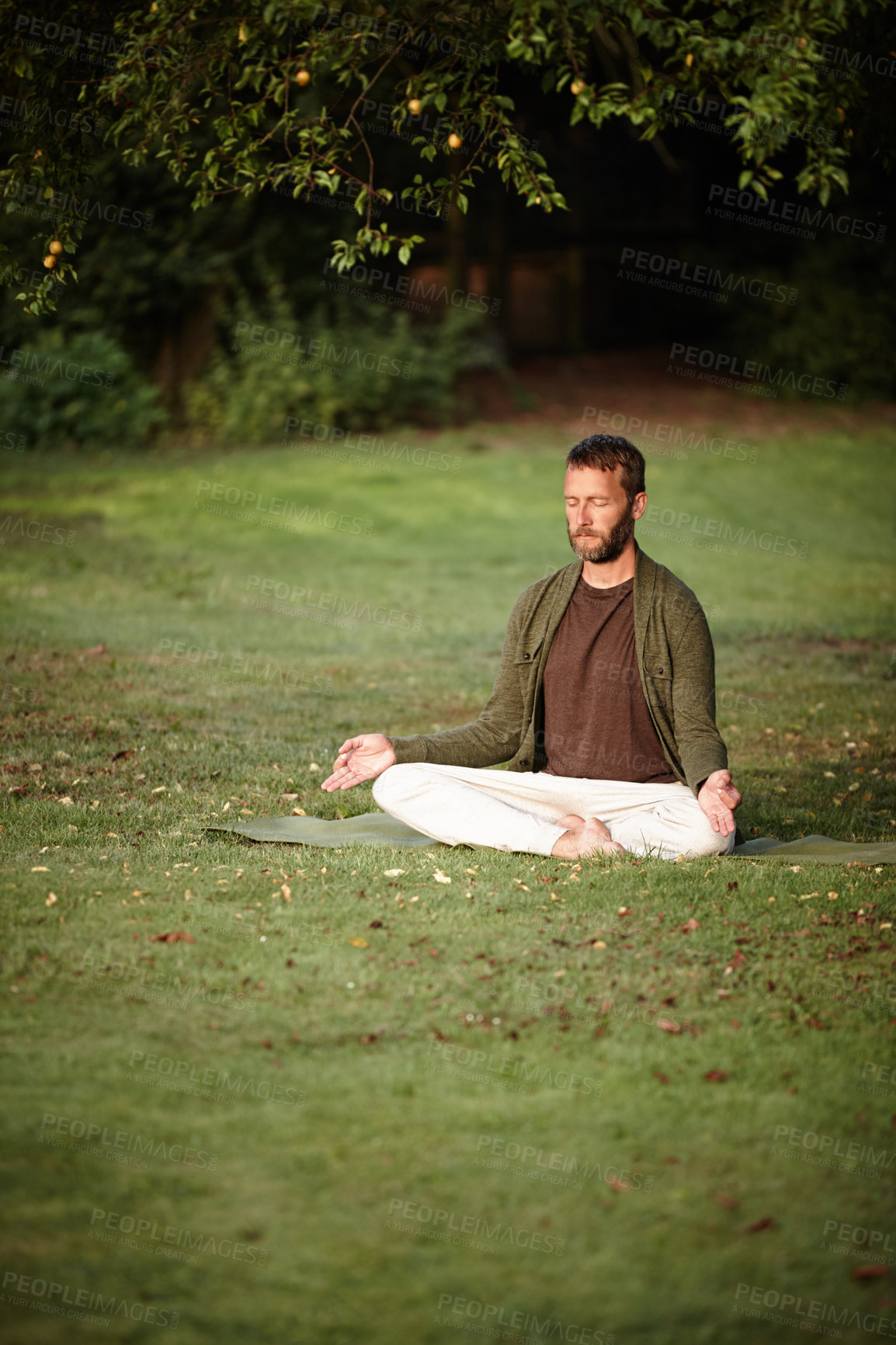 Buy stock photo Shot of a handsome mature man meditating in the lotus position in the outdoors