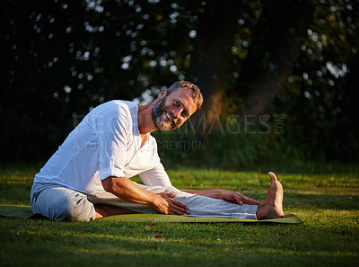 Buy stock photo Shot of a mature man doing yoga in a sitting position in the outdoors