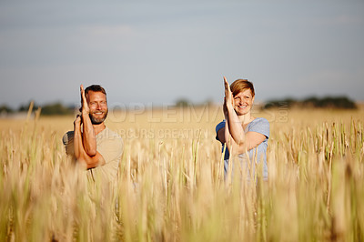 Buy stock photo Shot of a serene couple enjoying a yoga workout in a crop field