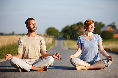 Buy stock photo Shot of a serene couple sitting in the lotus position on a country road