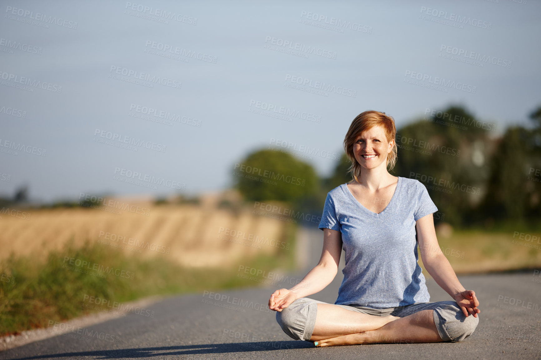 Buy stock photo Portrait of an attractive woman sitting in the lotus position on a country road