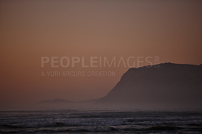 Buy stock photo Shot of a peaceful scene of ocean and distant mountains at dawn