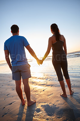 Buy stock photo Rearview of a couple watching the sunrise while holding hands