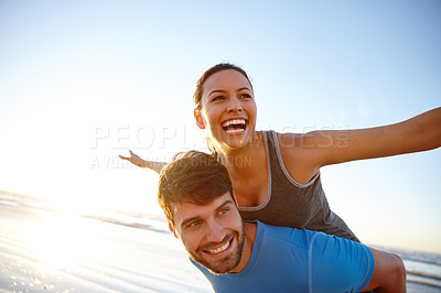 Buy stock photo Shot of a woman with her arms out while on her boyfriend's back on the beach