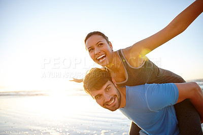 Buy stock photo Shot of a woman with her arms out while on her boyfriend's back on the beach