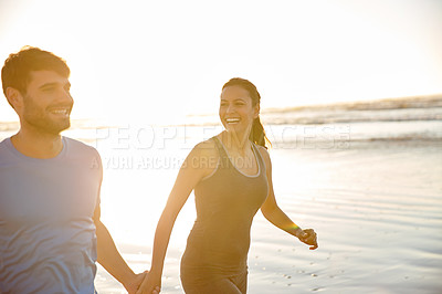 Buy stock photo Shot of a happy couple enjoying walking together on the beach at sunrise