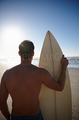 Buy stock photo Rearview shot of a young male surfer looking out at the beach and distant waves