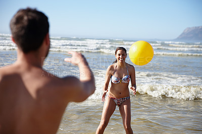 Buy stock photo Shot of a happy couple playing with a ball in the shallow water on the beach