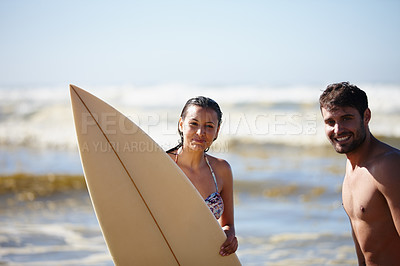 Buy stock photo Portrait shot of a happy young couple posing with a surfboard in the sea