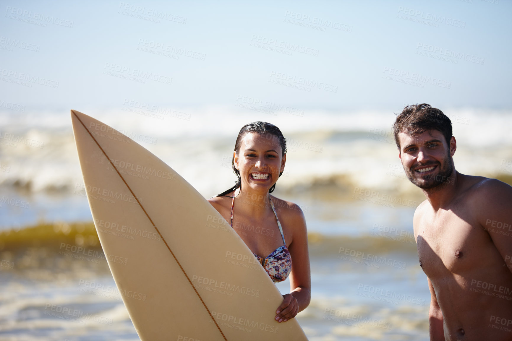 Buy stock photo Portrait shot of a happy young couple posing with a surfboard in the sea