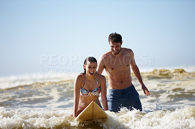 Buy stock photo Shot of a happy young woman being given a surfing lesson