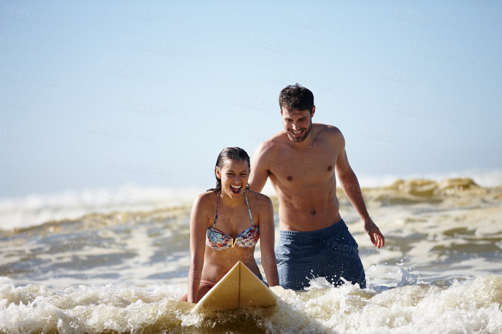 Buy stock photo Shot of a happy young woman being given a surfing lesson