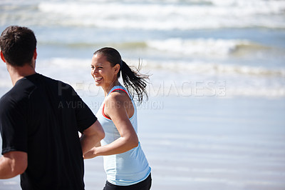 Buy stock photo Shot of a young couple running along a beach together