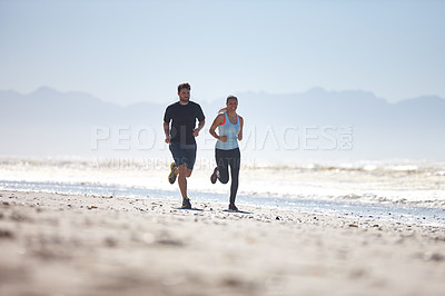 Buy stock photo Full length shot of a young couple running along a beach together