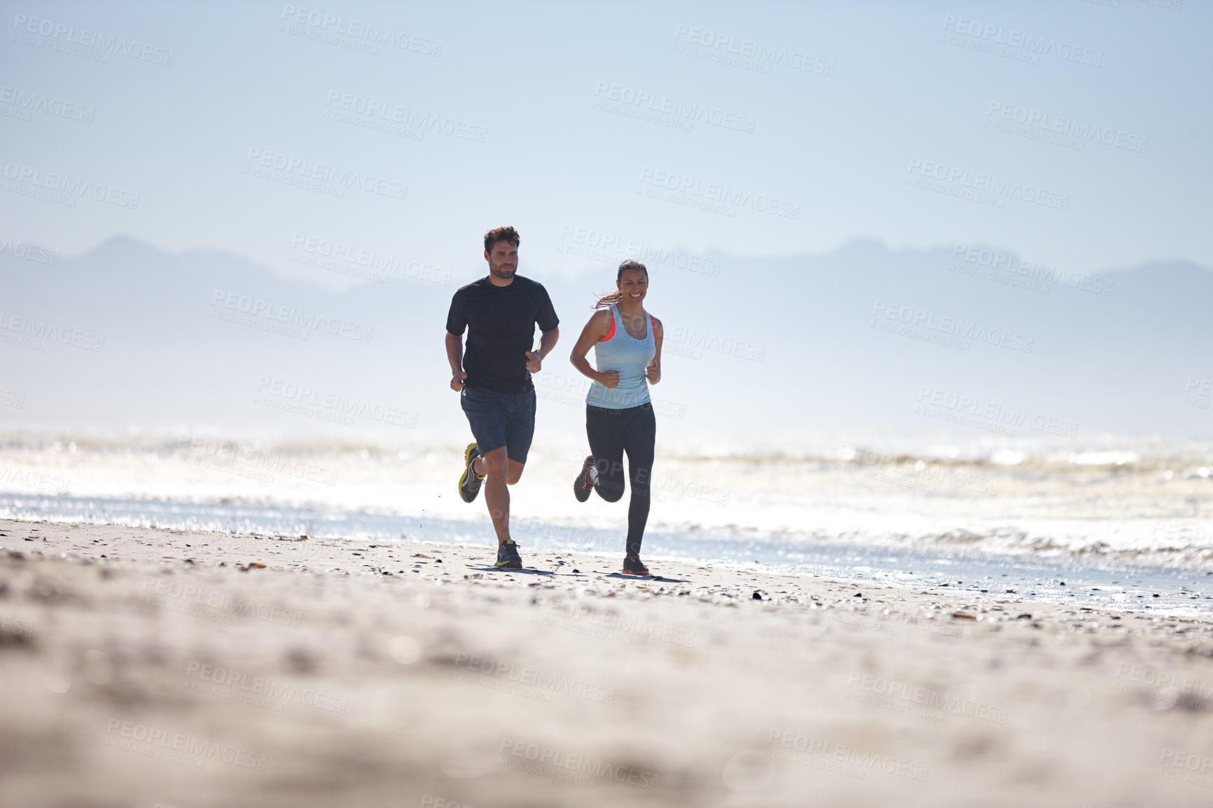 Buy stock photo Full length shot of a young couple running along a beach together