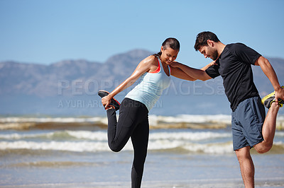 Buy stock photo Shot of a couple supporting each other as they warm up for a beach run