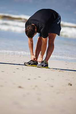 Buy stock photo Full length shot of a man warming up for a beach run