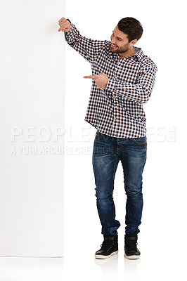Buy stock photo Studio shot of a handsome young man pointing towards the copyspace he's leaning on