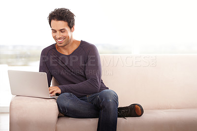 Buy stock photo Portrait of a handsome young man using his laptop at home