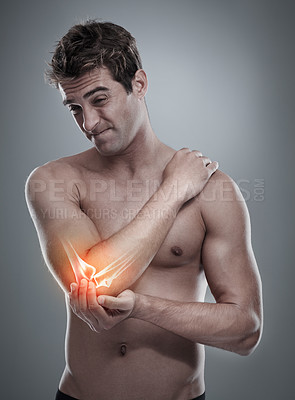 Buy stock photo A young man holding his inflamed elbow