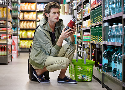 Buy stock photo Man, read and label in grocery store or decision, confused or choice. Male person, thinking and product in supermarket aisle for shopping nutrition value for food comparison, wholesale search or cost