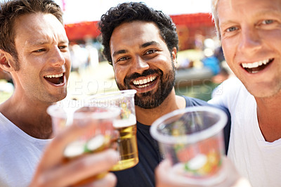 Buy stock photo Three young men toasting their beers at a music festival