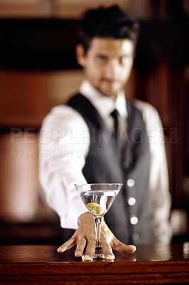 Buy stock photo Portrait of a handsome young bartender mixing a cocktail for a customer
