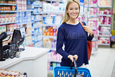 Buy stock photo Shot of a young woman browsing the shelves in a pharmacy