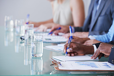 Buy stock photo Cropped shot of a row of businesspeople sitting with documents in front of them in a meeting