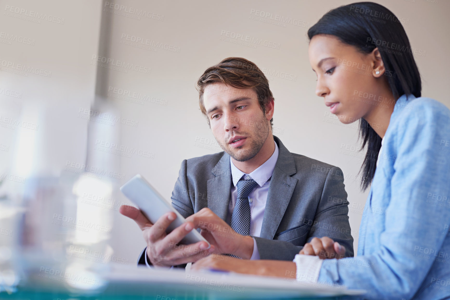 Buy stock photo Shot of two business colleagues talking at a table over a digital tablet