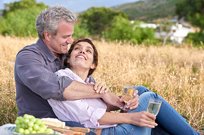 Buy stock photo Old couple, relax and picnic in park with drinks, love and celebration of marriage. Outdoor, man and woman on grass in nature with food, wine and support in retirement, holiday or hug on vacation