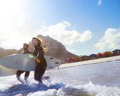 Buy stock photo Shot of an athletic young couple surfing at their favourite beach