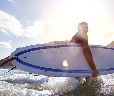 Buy stock photo Shot of a young male surfer carrying his surfboard while in the water