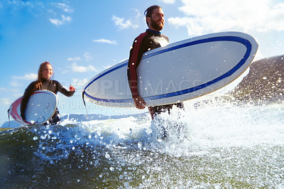 Buy stock photo Shot of an athletic young couple surfing at their favourite beach