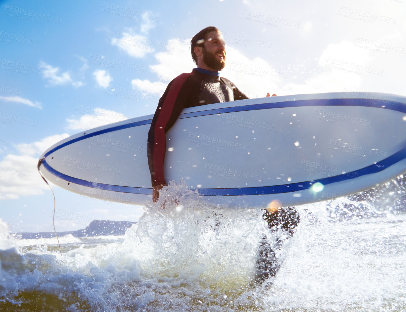 Buy stock photo Shot of a young male surfer carrying his surfboard while in the water