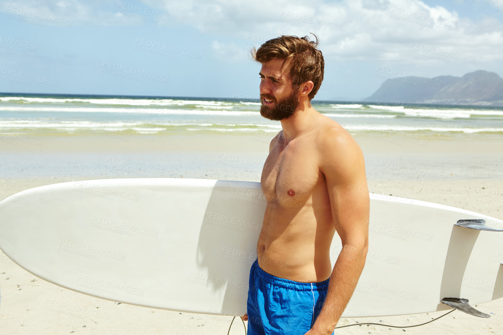 Buy stock photo Shot of a handsome young man standing with his surfboard on the beach